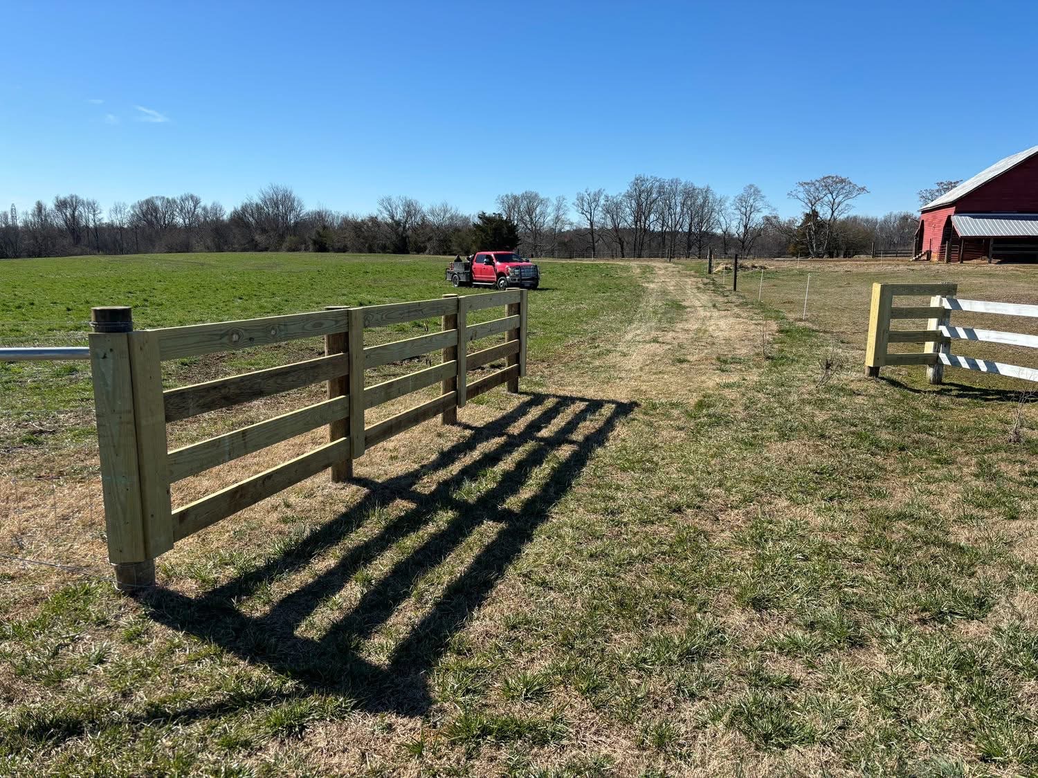 Farm gate with open field and red barn
